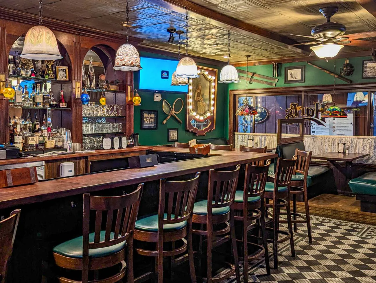 clickbizhub traditional pub interior of hart's Tavern featuring dark wood bar, green walls, nautical decor, vintage pendant lights, bar stools, and classic tavern atmosphere with multiple beer taps